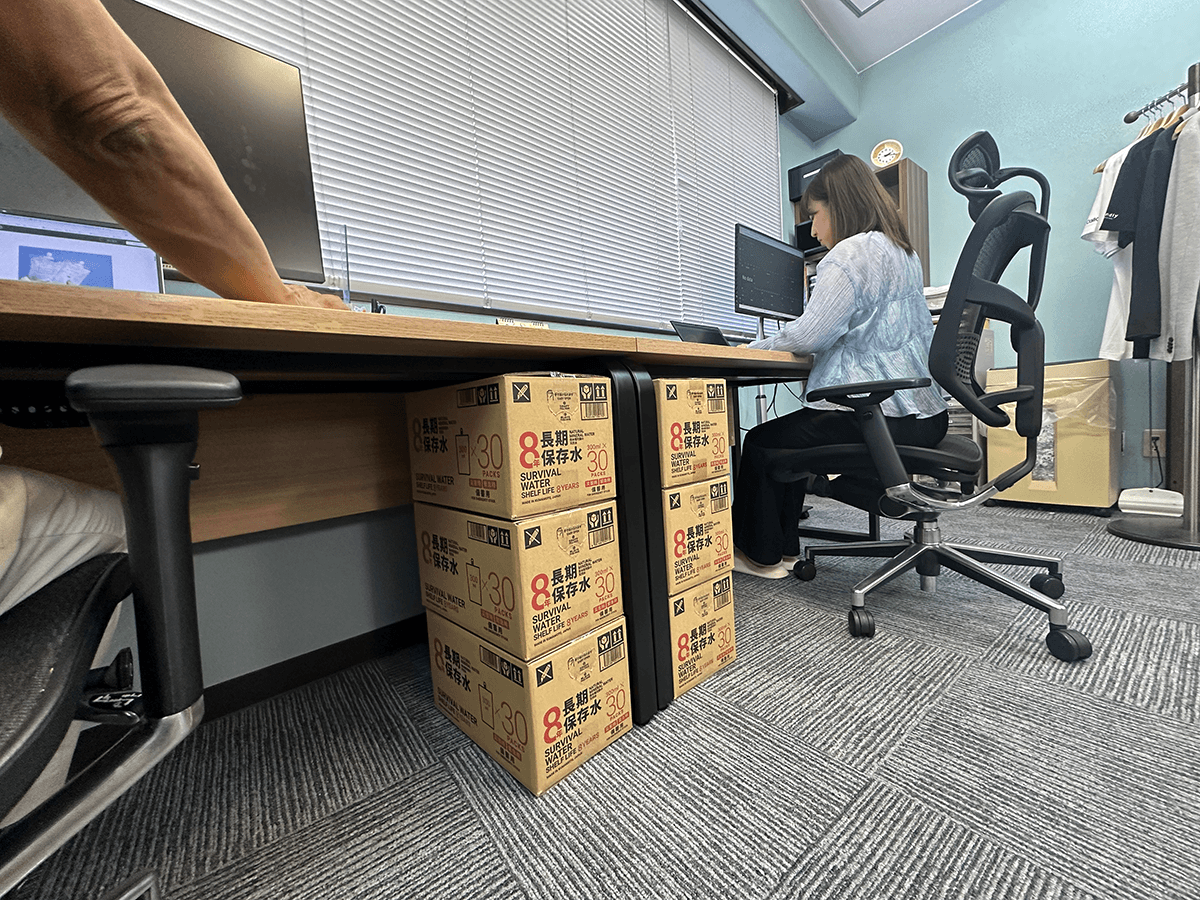 オフィスのデスク下に保存水を備蓄したイメージ